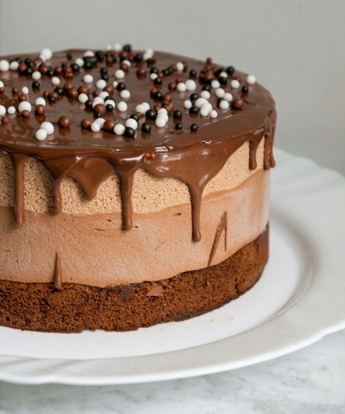 Chocolate mousse cake with ganache and chocolate pearl decorations, illustrating harmless secrets kept from partners.