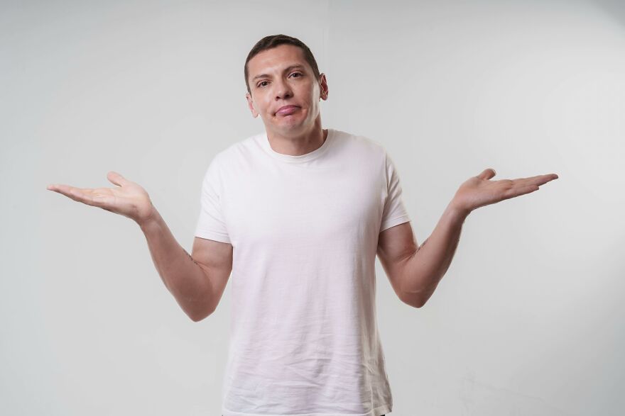 Man in a white t-shirt shrugging with both hands, illustrating small behaviors that make people like you more.
