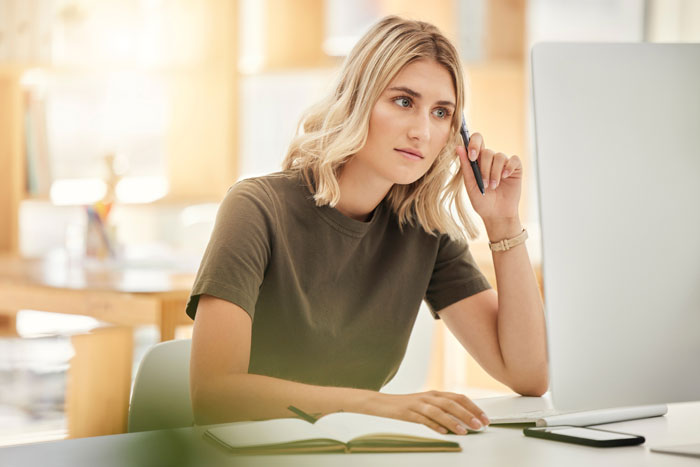 Mulher parecendo preocupada ao usar um computador, representando uma mãe que está tentando adotar seu 8º filho on-line. Mulher parecendo preocupada ao usar um computador, representando uma mãe que está tentando adotar seu 8º filho on-line.