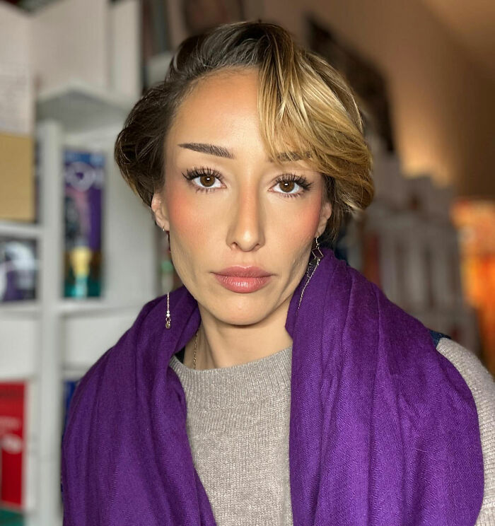 Young woman with short hair and purple scarf indoors, related to politician who called Ghislaine Maxwell his soulmate.