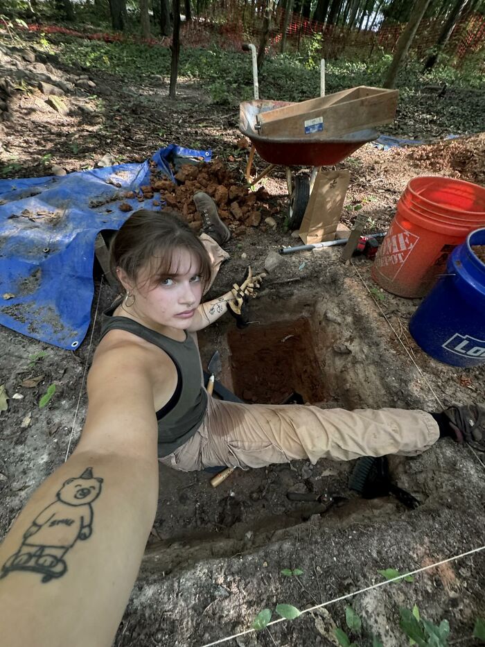 Young woman digging an archaeological site with power tools, embracing a hands-on technical and scientific role outdoors.