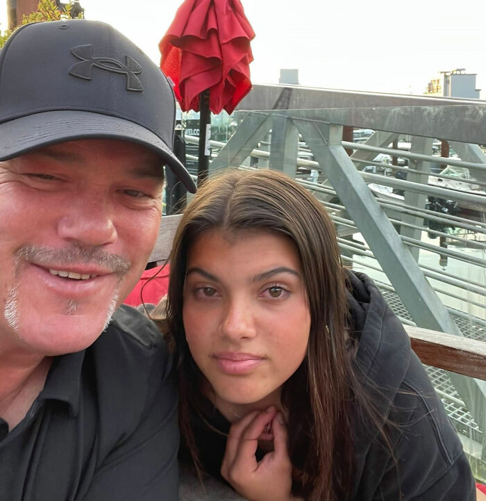 Man and young woman sitting outdoors at a marina with boats in the background, related to coroner releases cause of passing.