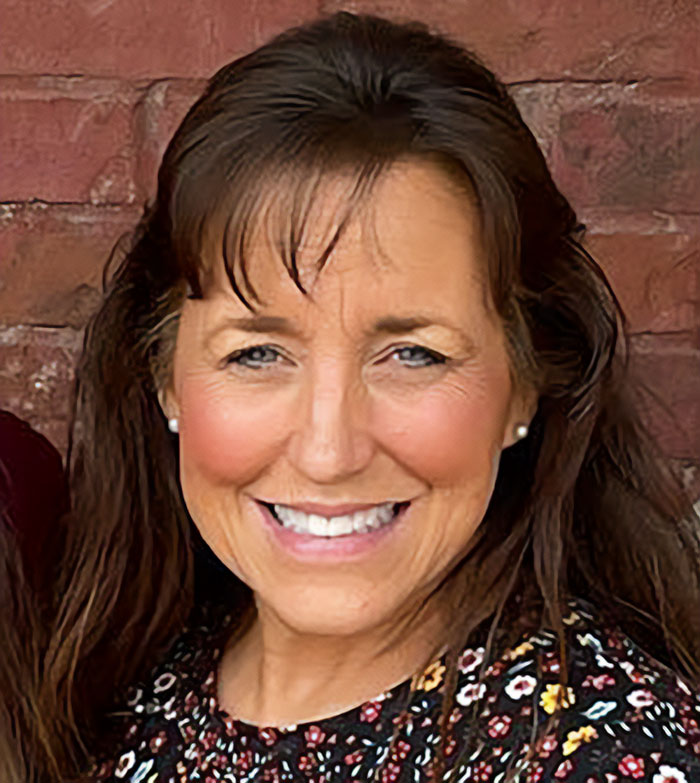 Michelle Duggar smiling against a brick wall, involved in a heated confrontation after bailing daughter-in-law out of jail.