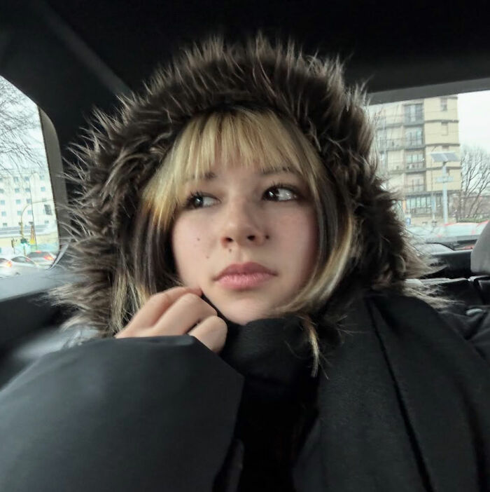 Alysa Liu wearing a fur-lined hooded coat, looking thoughtful during a car ride amid World Championships withdrawal.