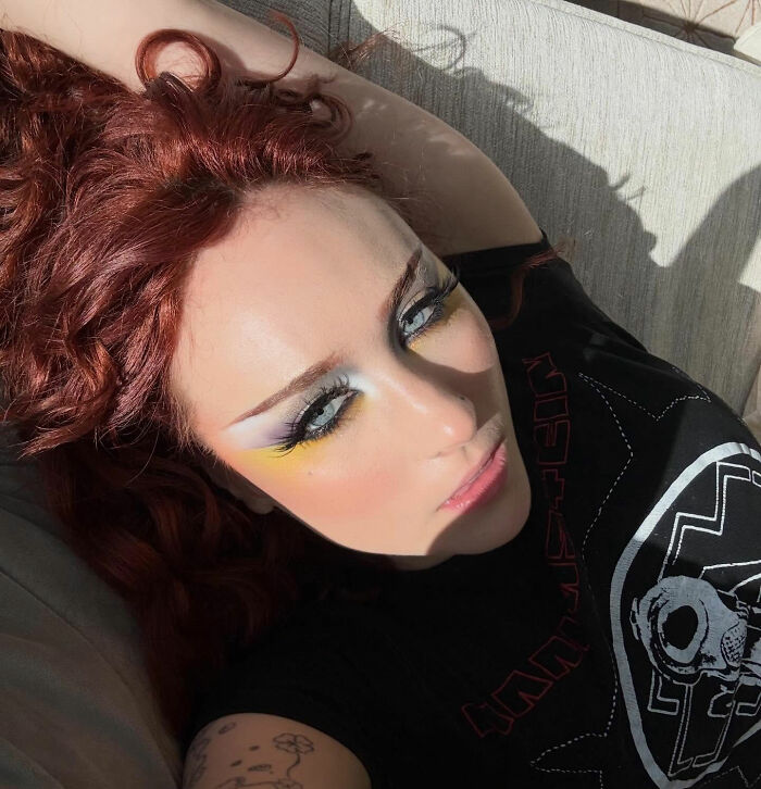 Chappell Roan deitado com maquiagem dramática e cabelo ruivo, destacando a polêmica da proibição do festival dos seguranças.