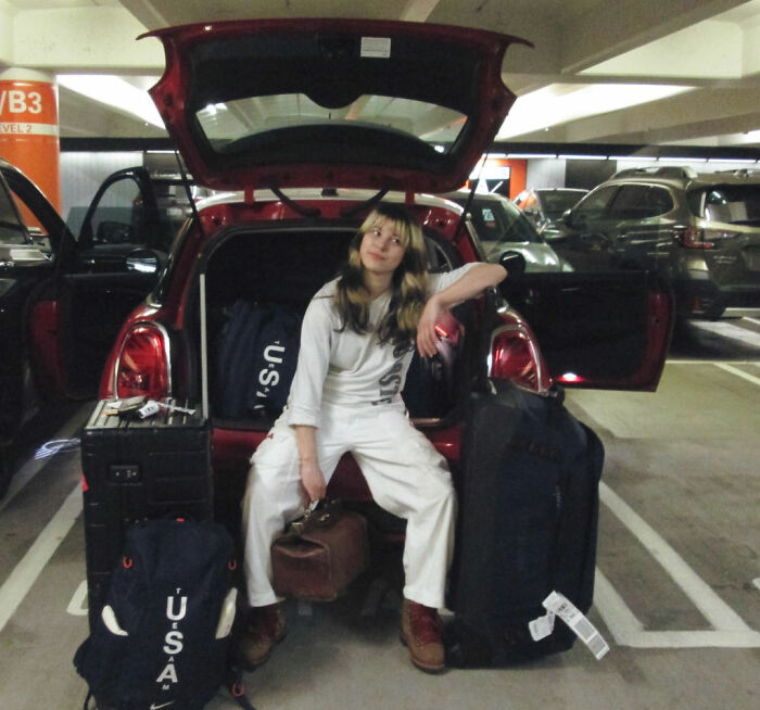 Alysa Liu sitting by an open car trunk surrounded by luggage in a parking garage after airport incident.
