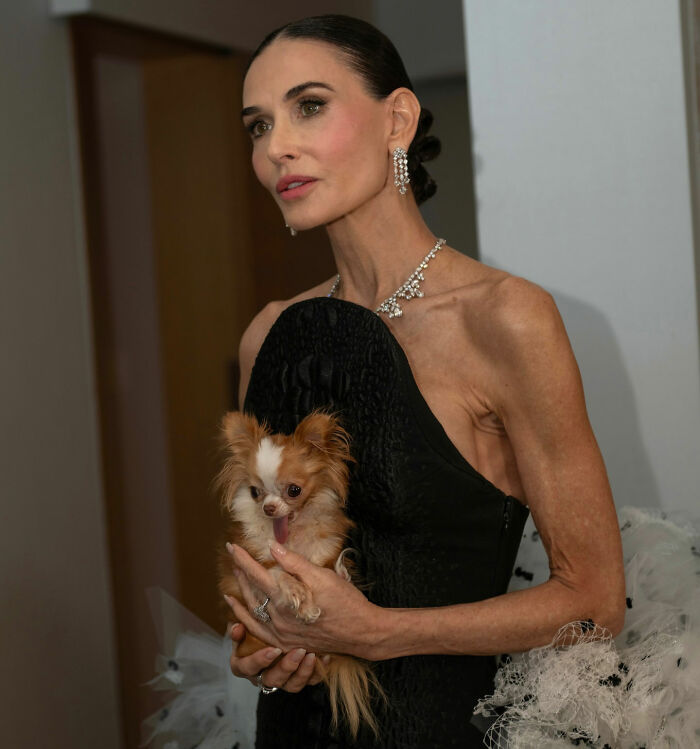 Demi Moore at SXSW wearing black dress and diamond jewelry, holding a small dog, sparking concern over weight loss.