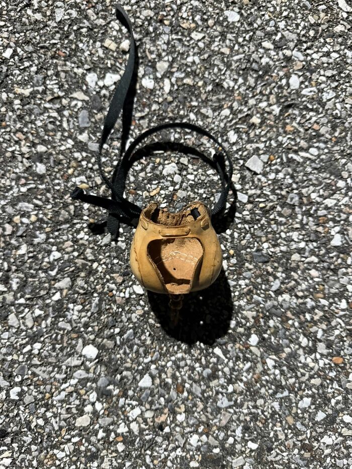 Worn leather object with straps lying on gravel, featured in internet mystery of unidentified objects solved.