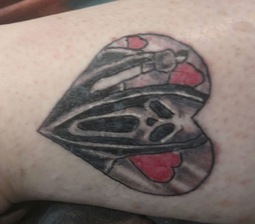 Heart-shaped tattoo featuring a skull design with red hearts, showcasing unusual tattoos that make you question the artists.