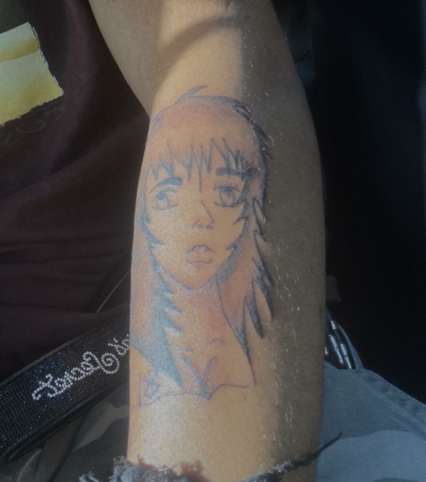 Tattoo on forearm featuring a poorly executed anime-style face, highlighting questionable tattoos and artists.