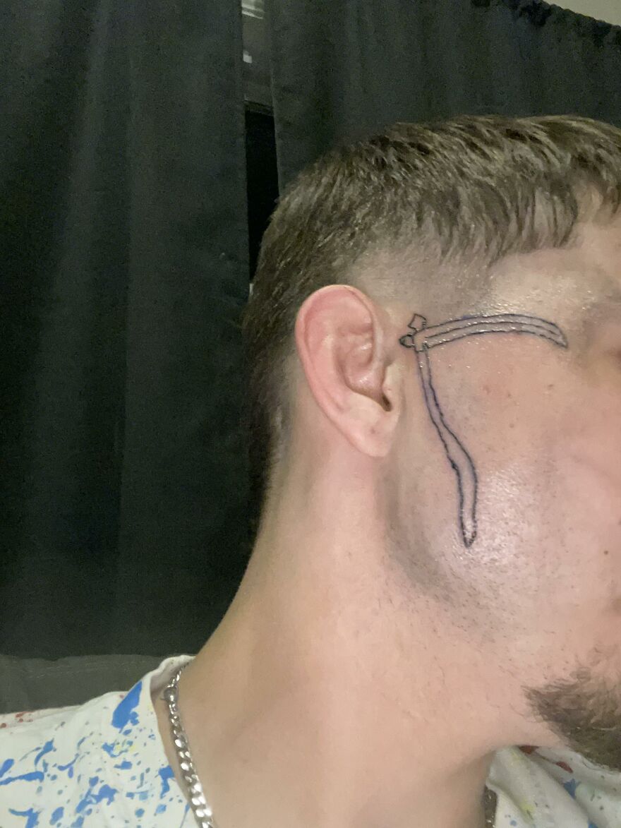 Side profile of a man with a questionable face tattoo resembling a simplified bow and arrow, showcasing unusual tattoos.