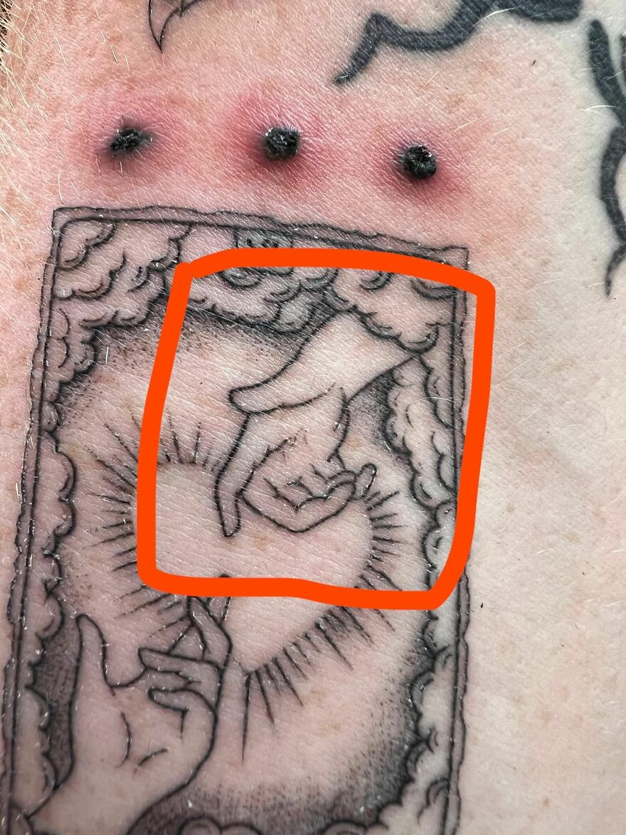 Close-up of a questionable tattoo showing two hands with an orange circle highlighting the design on skin.