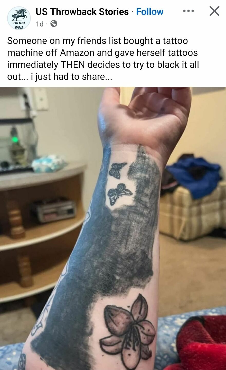 Arm tattoo with large black ink blotch covering butterfly and floral designs, showcasing questionable tattoo art and modifications.