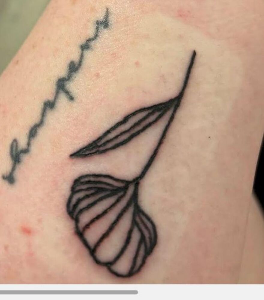 Minimalist black line tattoo of an abstract leaf design on light skin, showcasing unique tattoo art style.