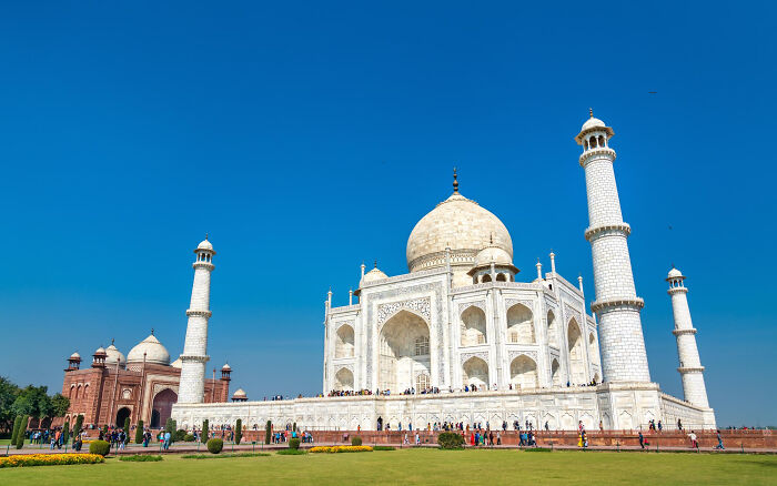 Taj Mahal under bright blue sky with tourists, illustrating popular myths about iconic landmarks around the world.