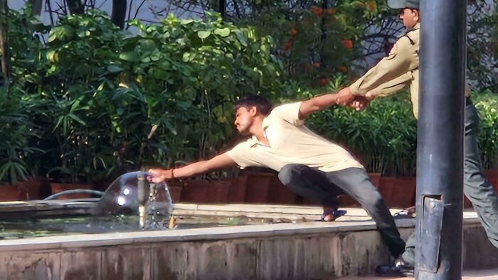 A man reaching for water while being held back, creating an accidental Renaissance style composition.