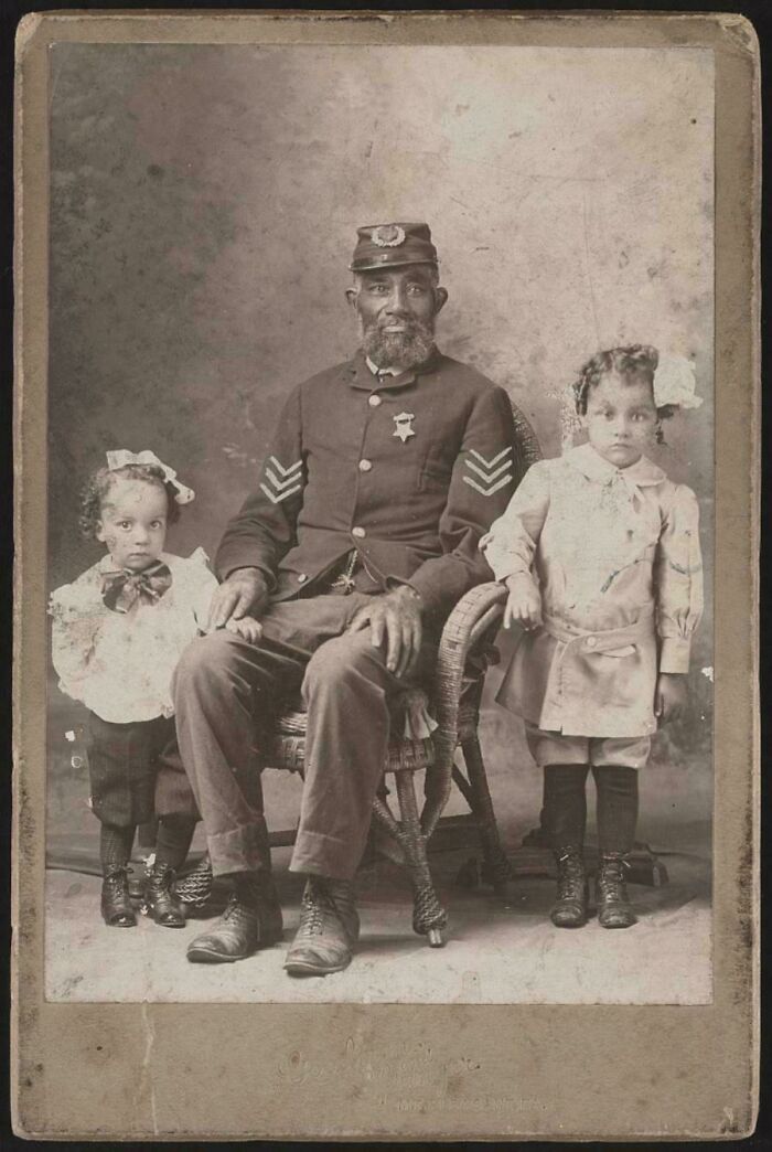 A candid old photo of a man in uniform with two young girls, revealing what the world looked like generations ago.