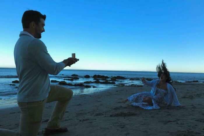 A beach proposal gone wrong as a woman falls, looking like an accidental Renaissance masterpiece.