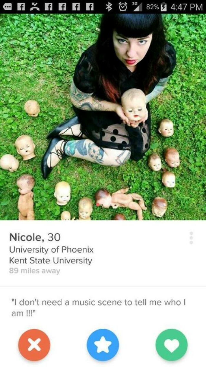 Woman with tattoos sitting on grass surrounded by creepy doll heads in a Tinder profile that made people cringe and laugh.