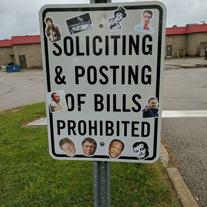 Street sign prohibiting soliciting and posting bills, humorously covered with sarcastic stickers of famous faces.
