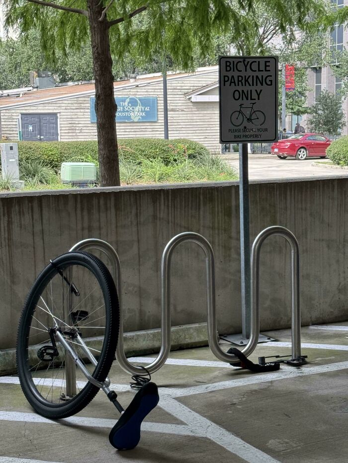 Bike parking with only one bike wheel locked to rack, illustrating sarcastic images about irony and parking fails.
