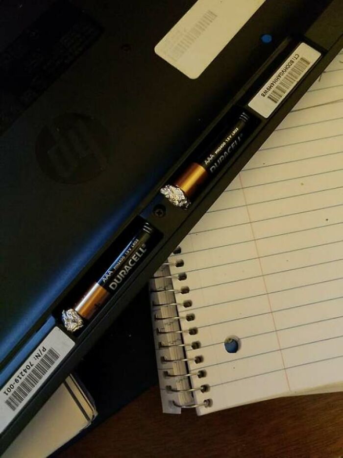 Laptop battery compartment with aluminum foil used to fix loose batteries, a genius idea solving an annoying problem.