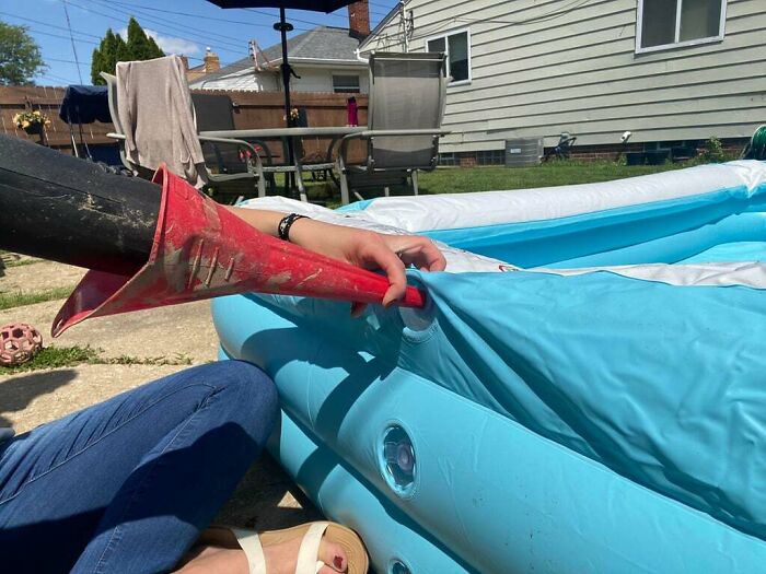 Using a funnel to easily inflate an inflatable pool with a leaf blower in an outdoor backyard setting.