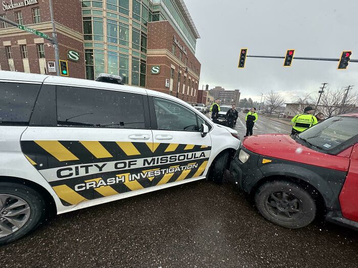City of Missoula crash investigation vehicle involved in a minor collision with a red SUV on a wet city street.