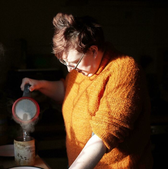 An accidental Renaissance style photo of a person pouring tea in a warm, dramatic spotlight