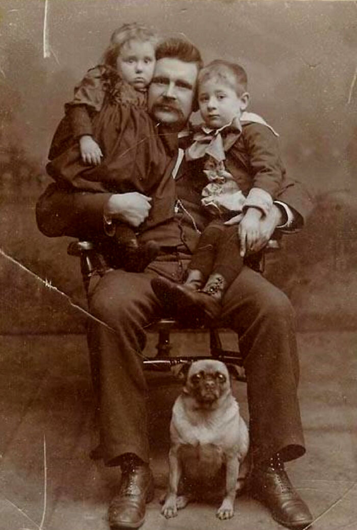 A candid old photo of a father with two children and a pug, revealing what the world looked like generations ago.