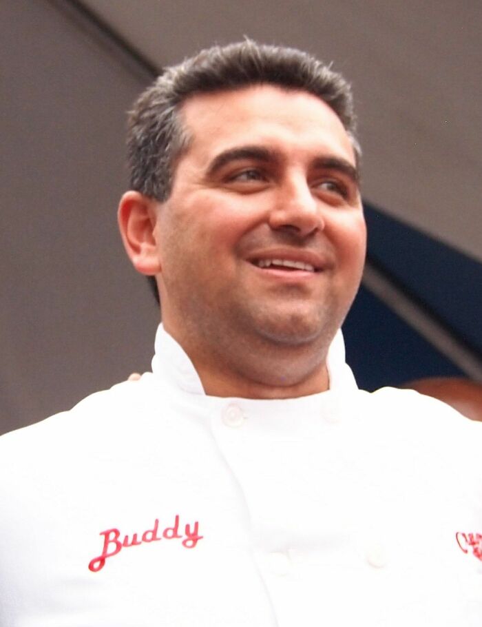 Buddy Valastro smiling in a white chef jacket, known for his baking career and TV show success.