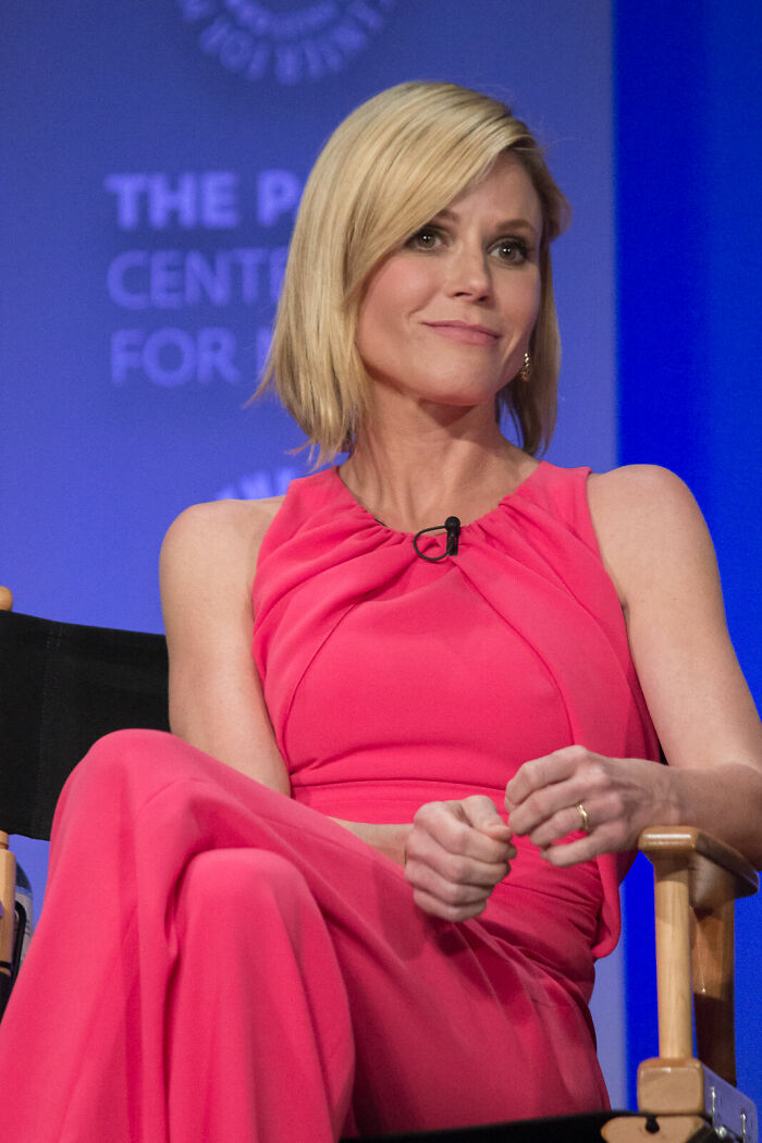 Julie Bowen sitting in a pink dress, speaking at a panel event discussing her bio and career highlights.