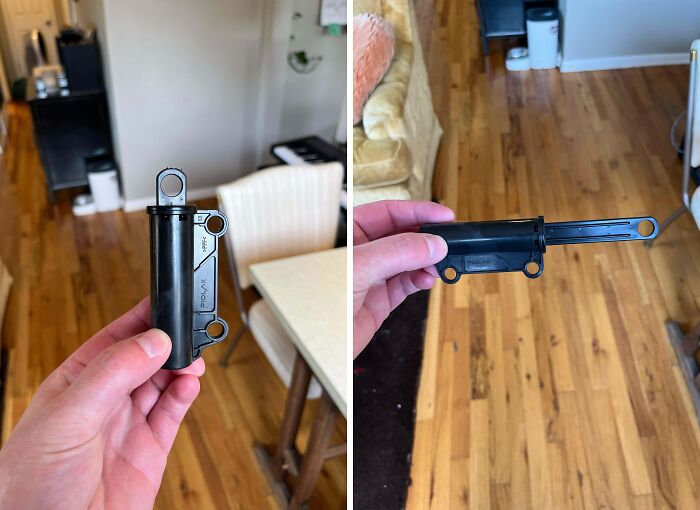 Hand holding unidentified black plastic object with pulled-out sliding part on wooden floor, internet mystery solved.