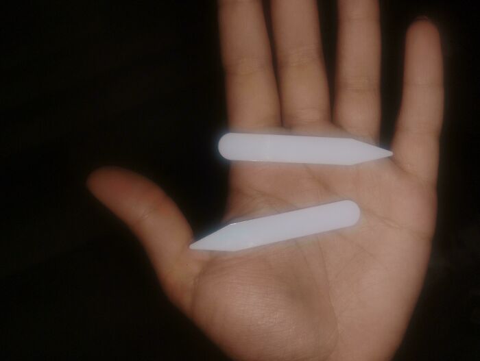 Hand holding two small white unidentified objects, illustrating internet mystery solving of unidentified objects.