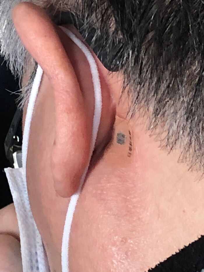 Close-up of a person's ear and neck with a small unidentified object tattoo behind ear, related to internet mystery-solving.