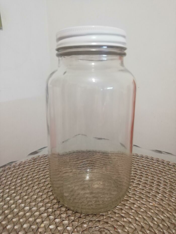 Empty glass jar with white lid placed on woven surface, illustrating a scientific facts concept to blow your mind.