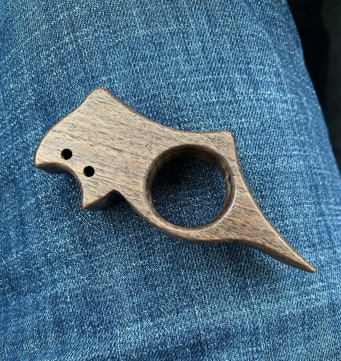 Wooden unidentified object with a circular hole, resting on blue denim jeans, an example of internet mystery solved.