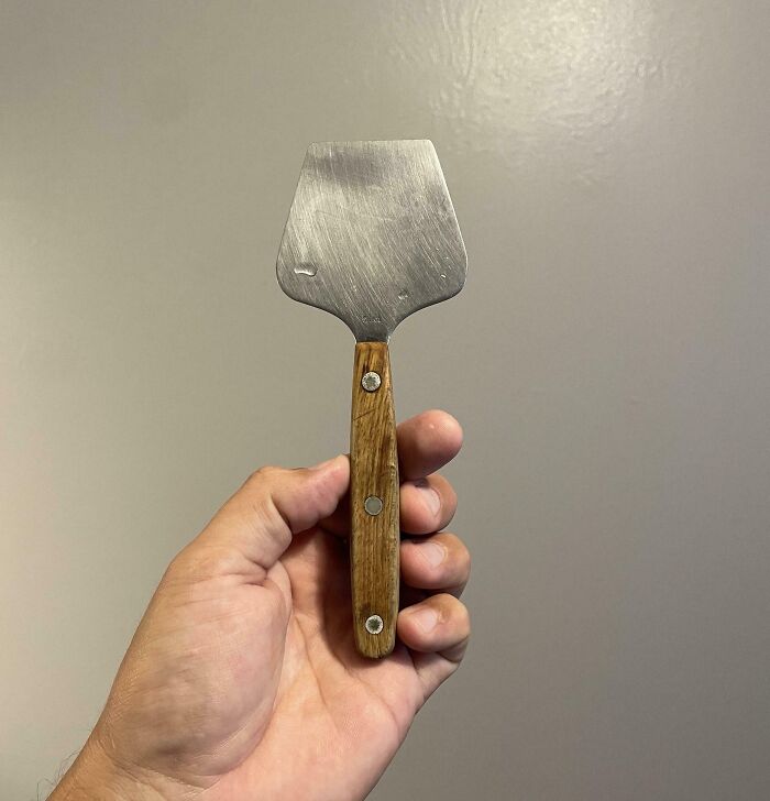 Hand holding a wooden-handled metal tool, showing an unidentified object solved by the internet mystery keywords.