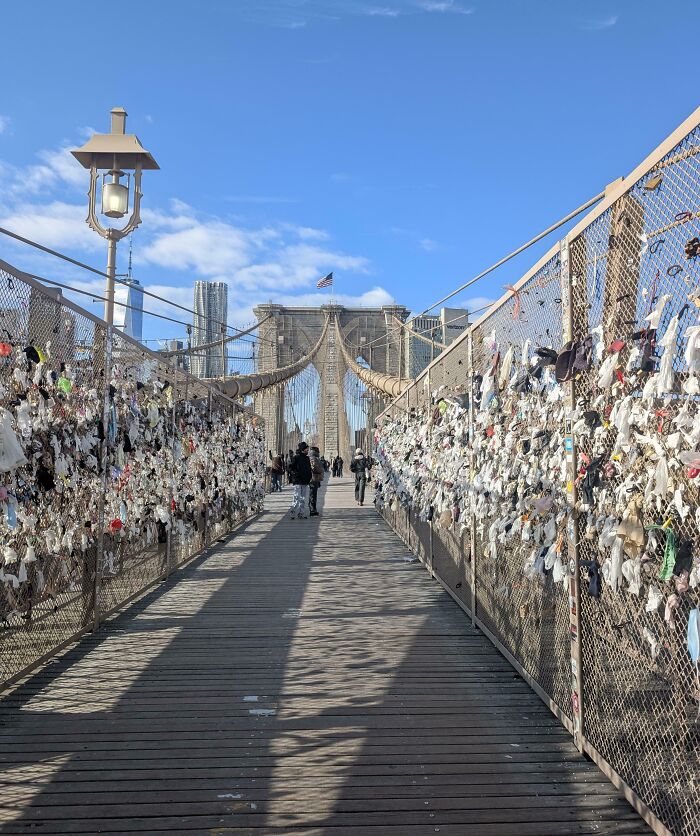 Brooklyn Bridge walkway covered with trash and debris left by tourists, showing rude and entitled behavior in public spaces.