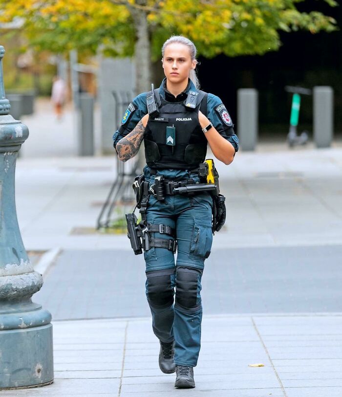 Female police officer walking confidently on a city street, representing women choosing power tools and lab coats careers.