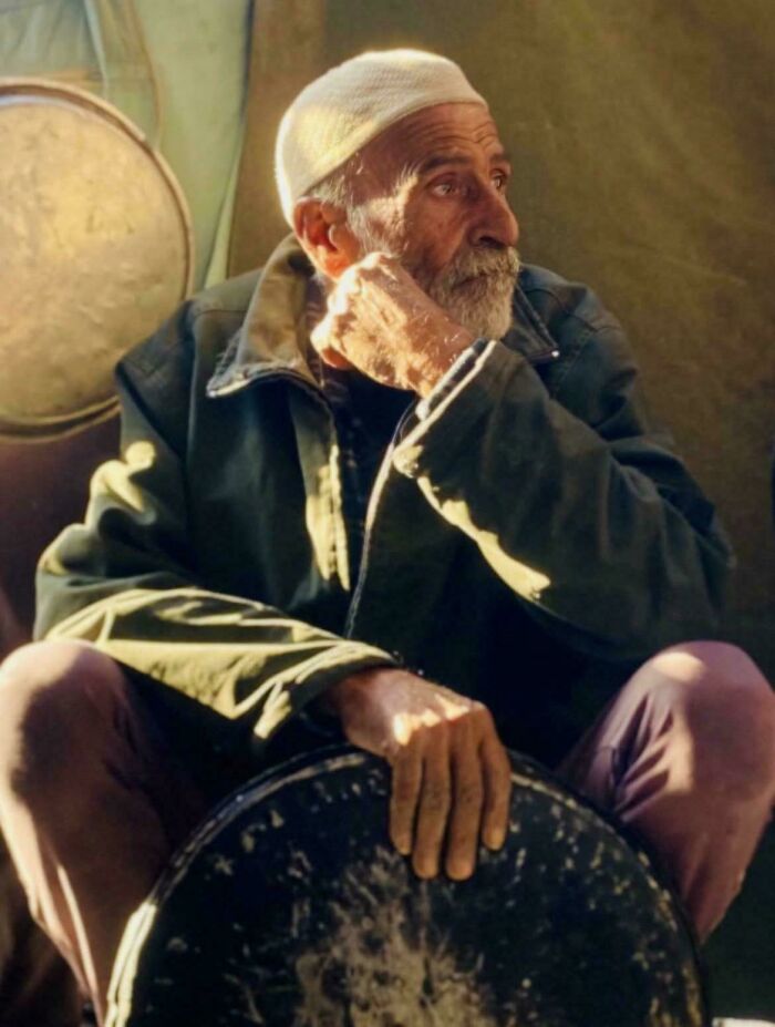 An accidental Renaissance portrait of an elderly man with a white cap sitting thoughtfully in warm light