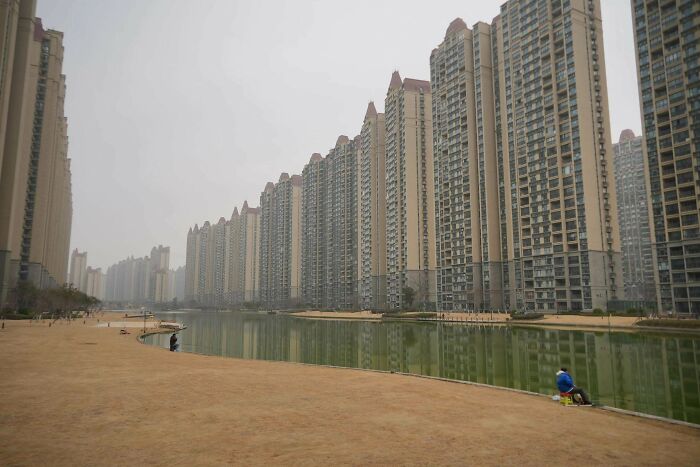 Weirdly eerie urban hell with repetitive high-rise apartments reflected over water