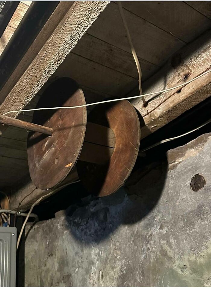Old wooden spools mounted in a dim basement, one of the disturbing and weird things found in abandoned homes.