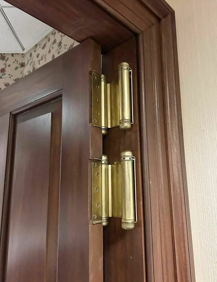 Close-up of unusual gold door hinges on a wooden door frame found in an abandoned or forgotten home.