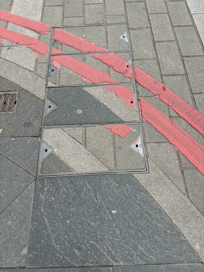 A funny 'you had one job' fail where red hazard lines are painted incorrectly over manhole covers on a sidewalk.