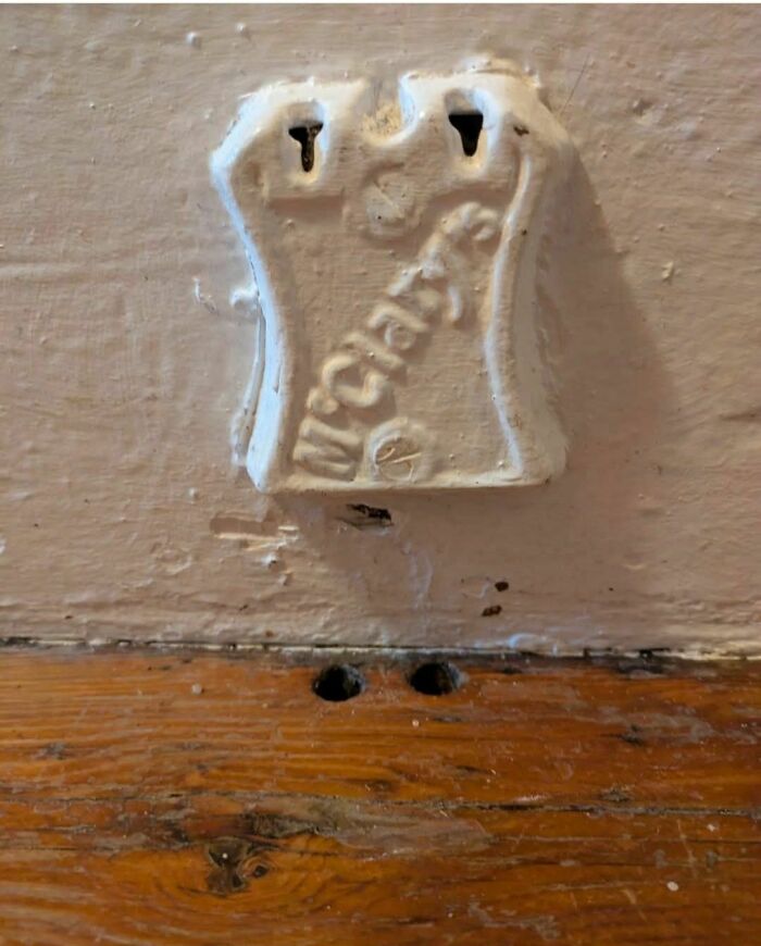 Old rusty metal fixture attached to a wall above a wooden floor in an abandoned or forgotten home.