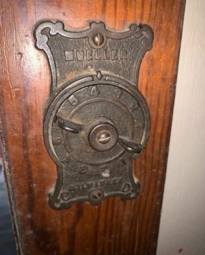 Rusty antique Mueller lock on wooden door found in abandoned homes showing disturbing and weird forgotten objects.