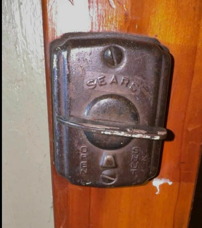 Rusty old Sears door lock on a wooden door, one of the disturbing and weird things found in abandoned homes.
