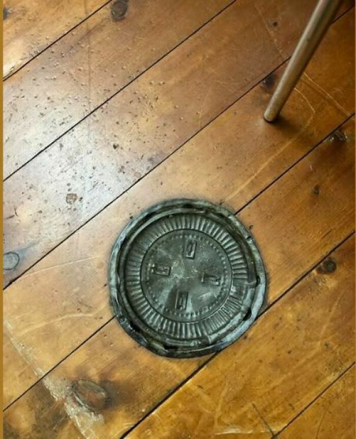Circular metal object embedded in wooden floor, one of the disturbing and weird things found in abandoned homes.
