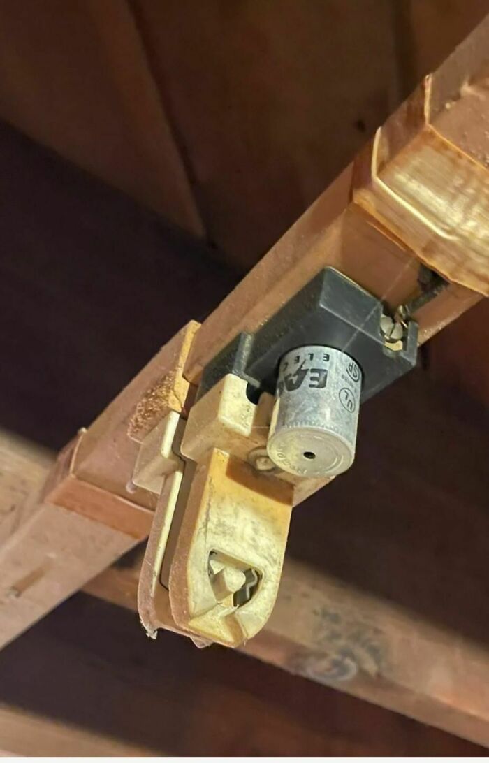 Old dusty and rusty electrical component found in an abandoned home with wooden beams and worn surfaces.